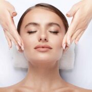 Cute  young girl with thick eyebrows and perfect skin doing facial massage, closed eyes, relaxing, beauty photo concept, stress free.